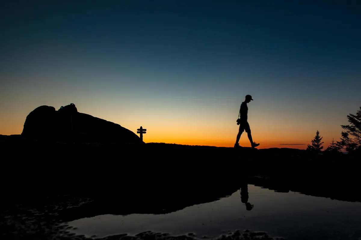 Silhouette of a hiker walking along a ridgeline at sunset