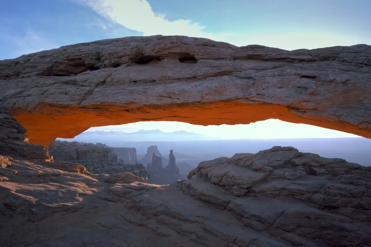 a broad stone arch with rock pinnacles in the distance