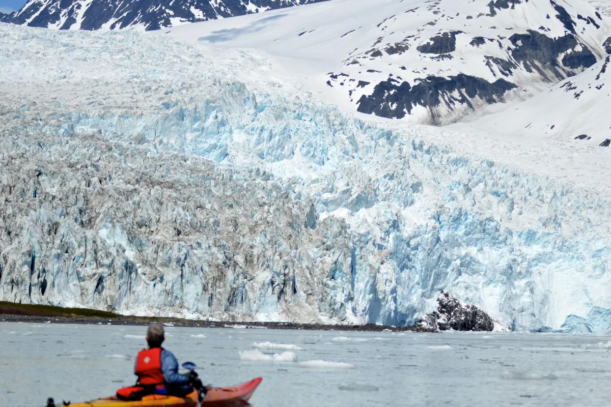 A kayaker views a tidewater glacier in the distance