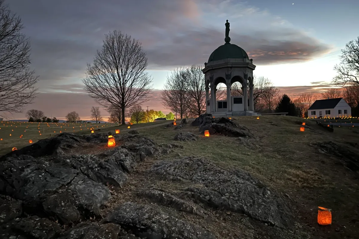 luminaries placed by Maryland Monument with dramatic orange red clouds