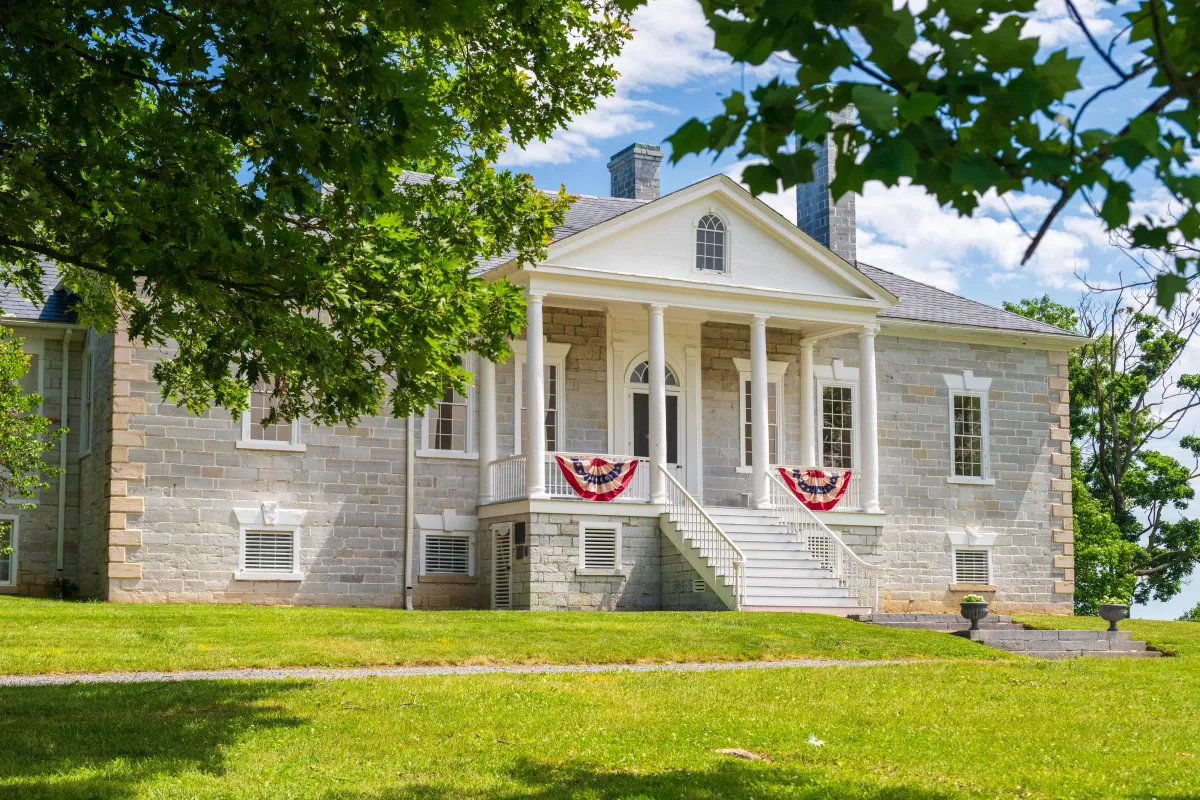American flag bunting hangs from the porch on a limestone building with a white portico.