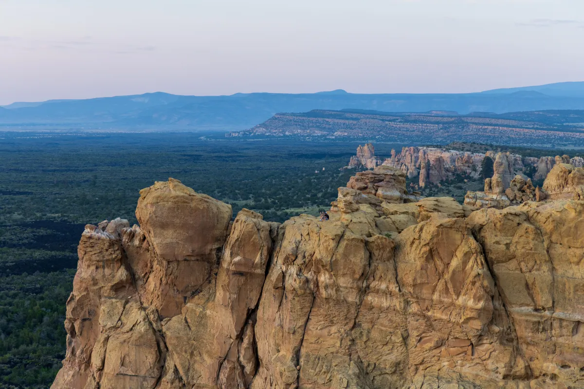 Yellow sandstone cliff at sunset with dark lava field in background