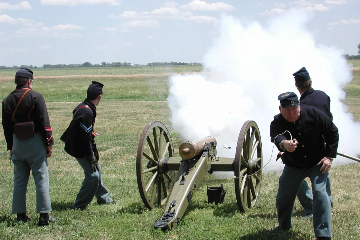 Men in 19th century U.S. Army uniforms fire a reproduction period cannon.