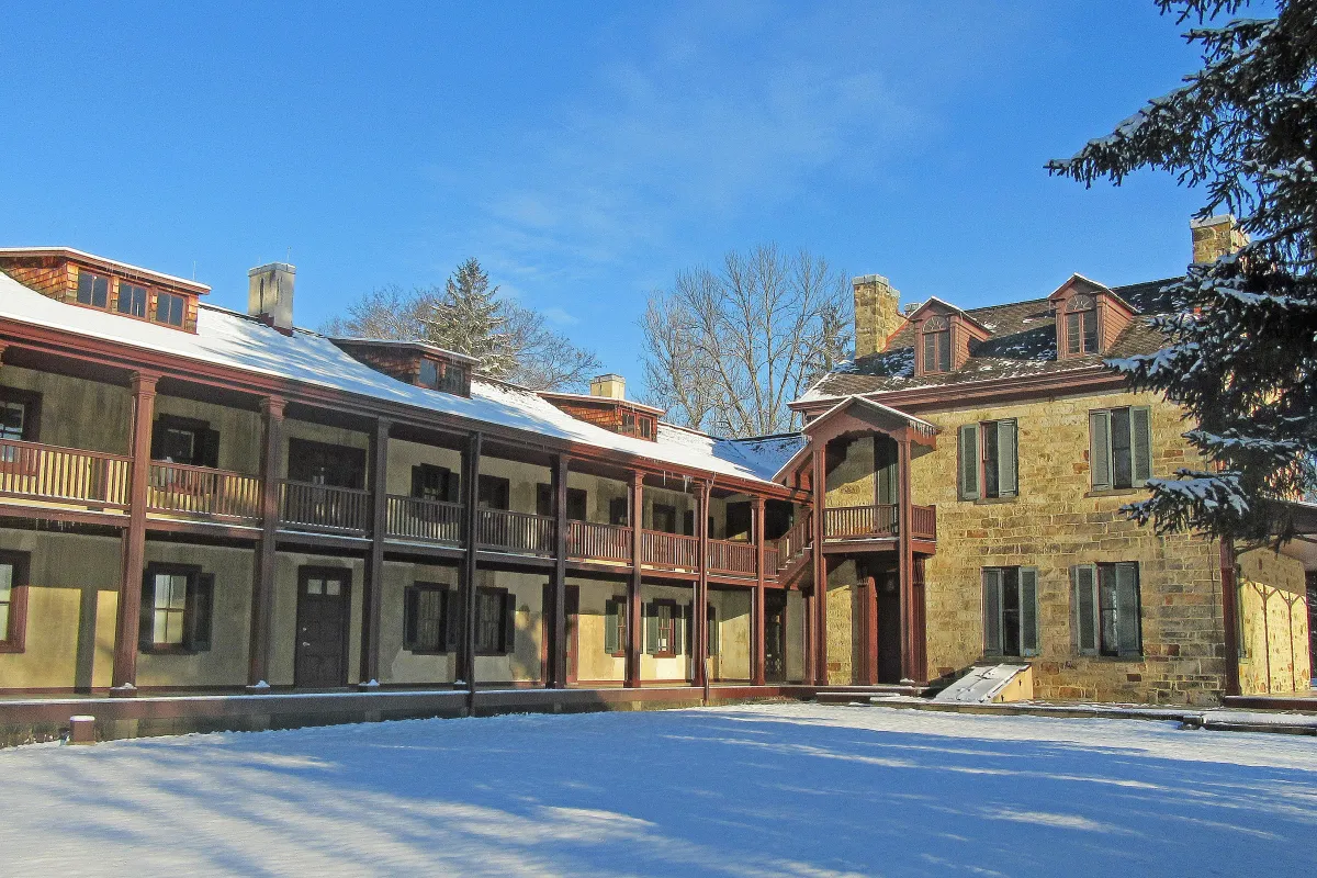 Gallatin House - Stone House and South Wing in snow with blue sky