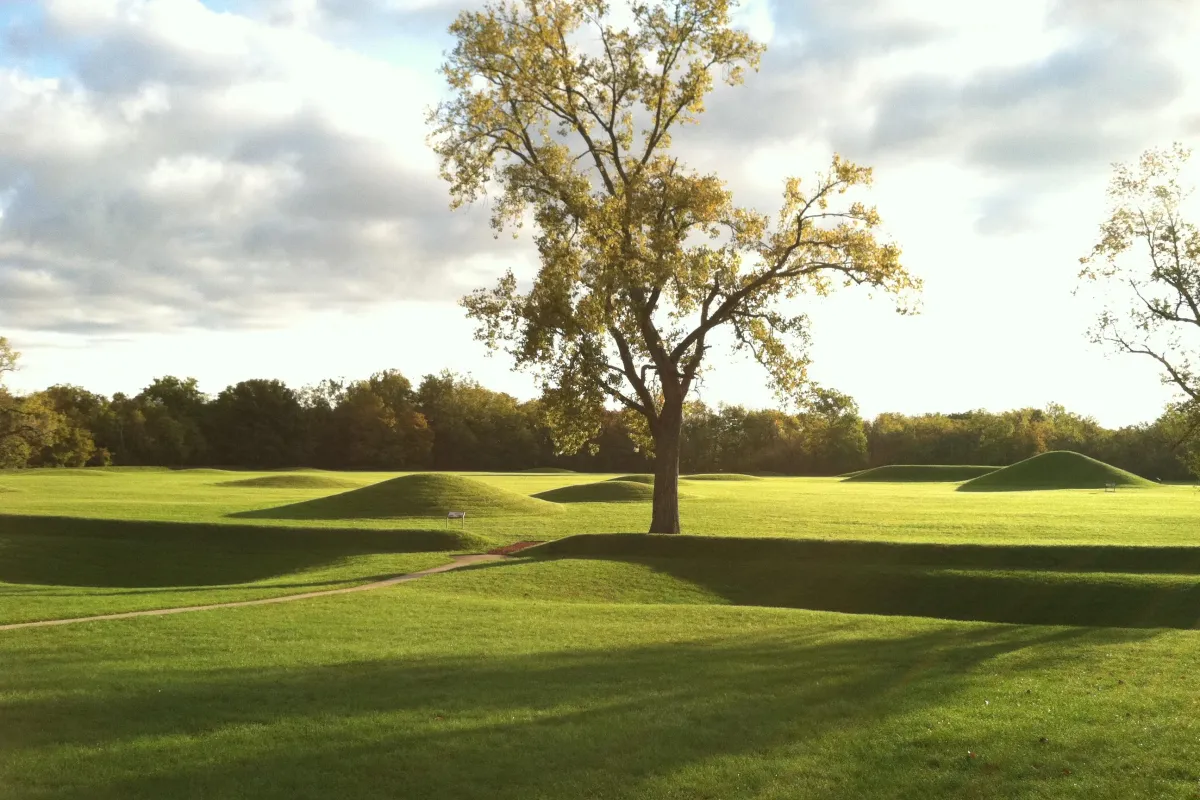 An early morning sun casting long shadows over grass-covered mounds.