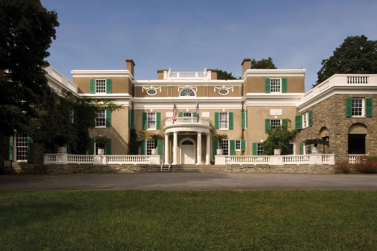 A stucco and fieldstone house with white trim and circular portico.