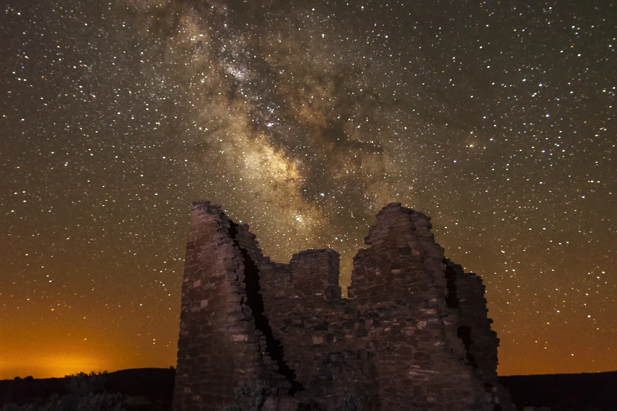 a stone structure at night with the Milky Way arcing overhead