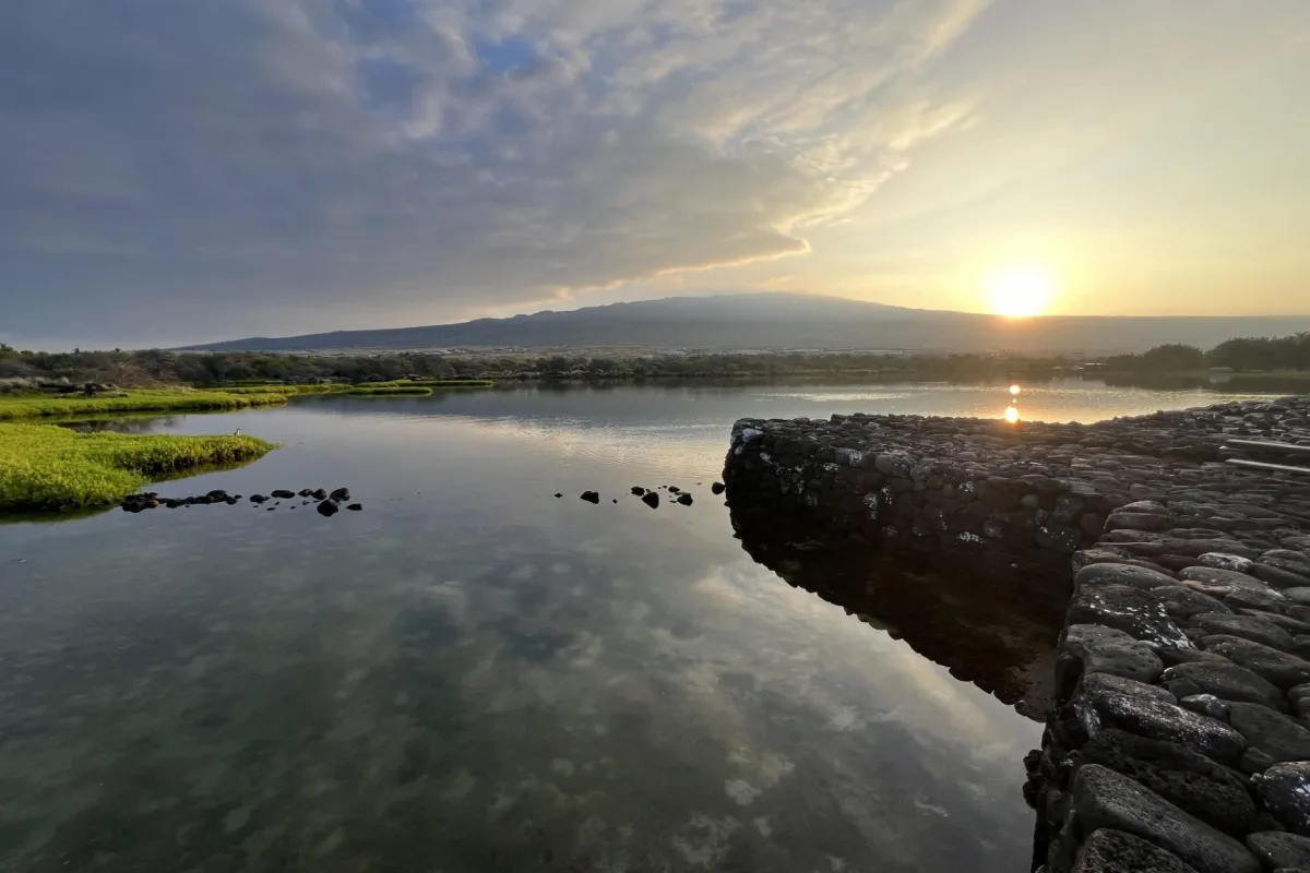 Sun rises over Hualālai volcano as seen from the Kaloko fishpond wall