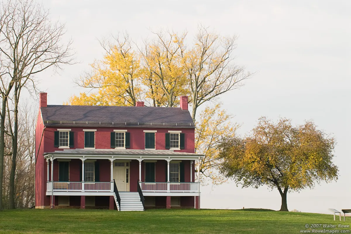 Federal style house with trees behind it during the fall season.