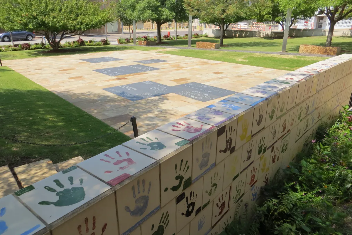 Tiles with hand prints and chalkboards set into the ground for children.