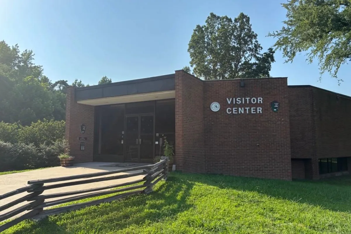 Pictured is the front of the brick visitor center under a cloudless blue sky.