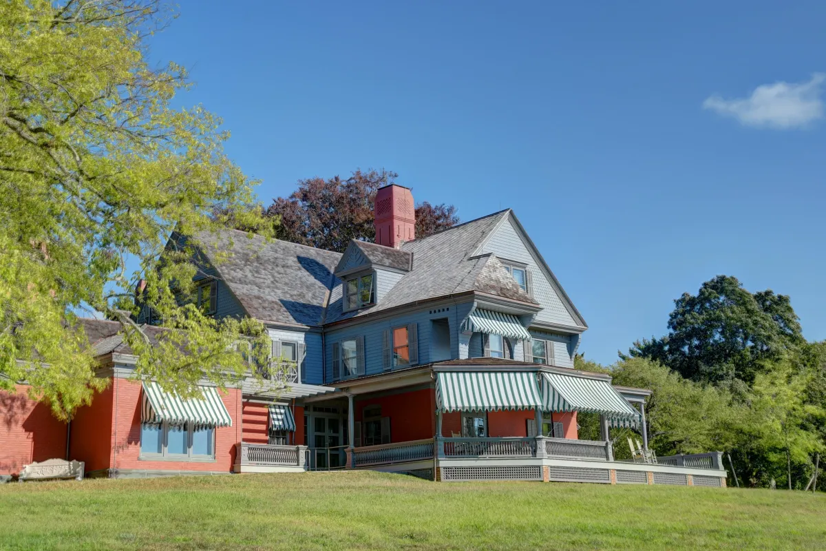 A large house painted gray with green lawn and trees.
