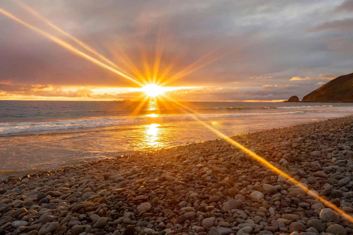 Sunbeams reaching from glowing sun over the ocean.