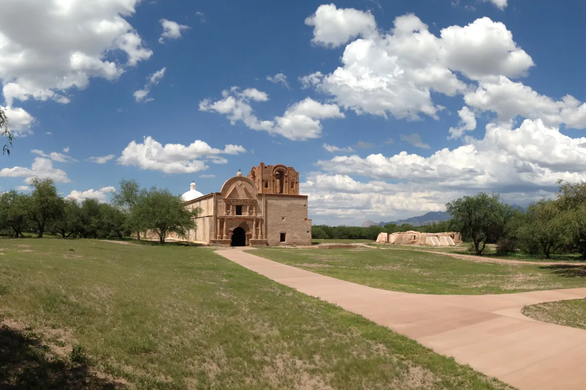 panorama of mission church with green grass and clouds
