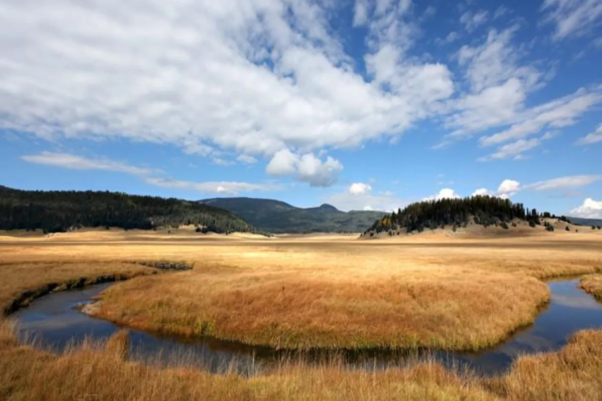 Scattered clouds over landscape view of winding river and brown grasslands